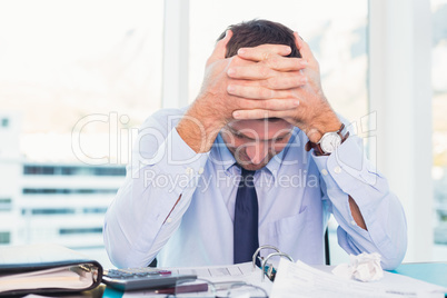 Stressed businessman with head in hands