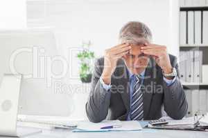 Stressed businessman with head in hands