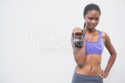 Fit woman smiling at camera holding kettlebell