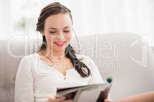 Pretty brunette reading magazine on the couch