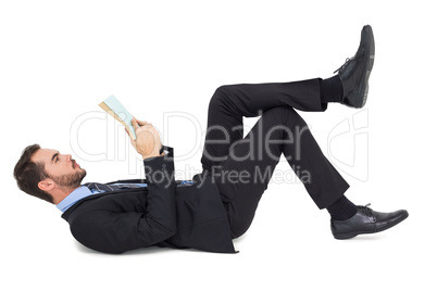 Businessman lying on the floor while reading a book