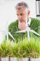 Casual businessman looking at model wind turbines