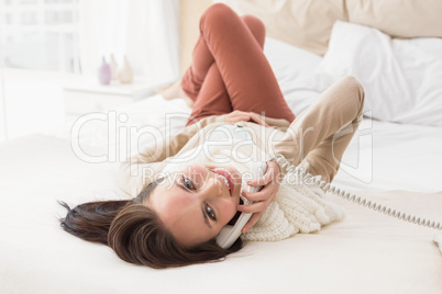 Pretty brunette making a phone call on bed