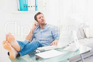 Businessman on the phone using his computer with his feet up