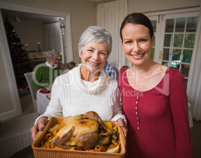 Women posing with roast turkey in front of their family