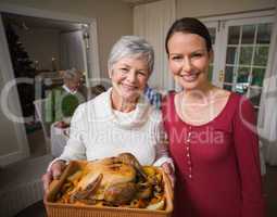 Women posing with roast turkey in front of their family