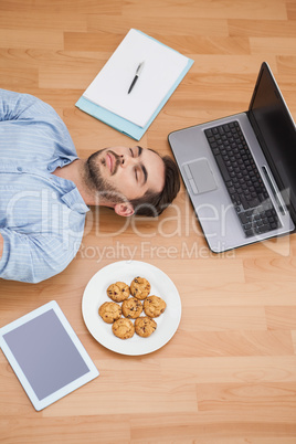 Casual man lying on floor surrounded by his possesions