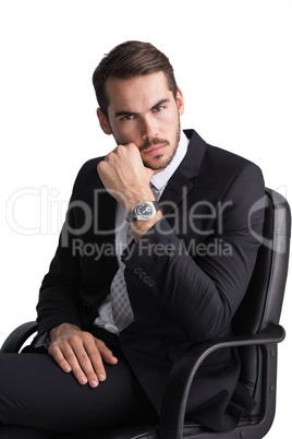 Serious businessman sitting on office chair posing