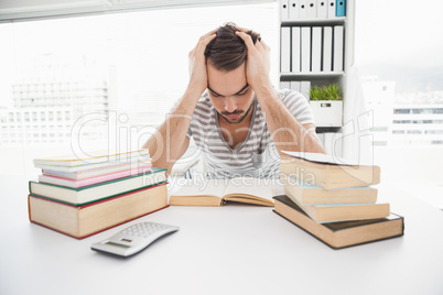 Stressed casual businessman studying at his desk