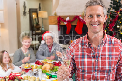 Smiling father toasting at camera in front of his family