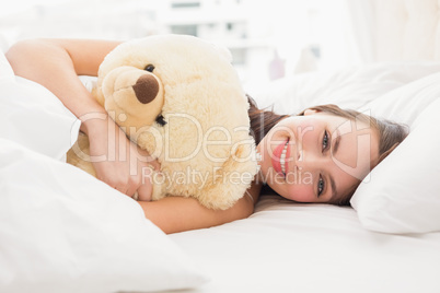 Pretty brunette under the duvet with teddy bear