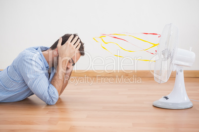 Casual man lying in front of fan