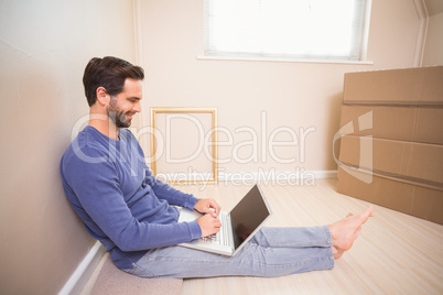 Casual man using laptop after moving in