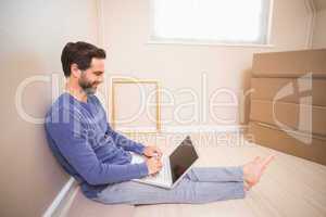 Casual man using laptop after moving in