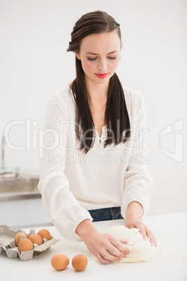 Pretty brunette making dough on counter