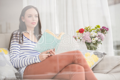 Pretty brunette reading book on couch