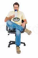Man sitting on chair shouting through megaphone