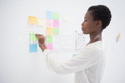 Pretty designer looking at sticky notes on window