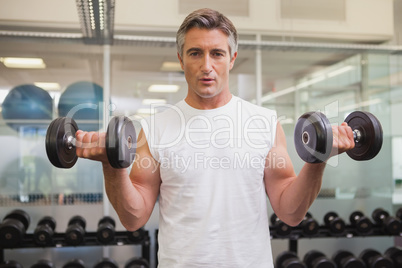 Fit man lifting heavy black dumbbells