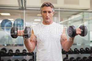 Fit man lifting heavy black dumbbells