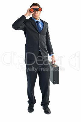 Businessman using binoculars while holding a briefcase