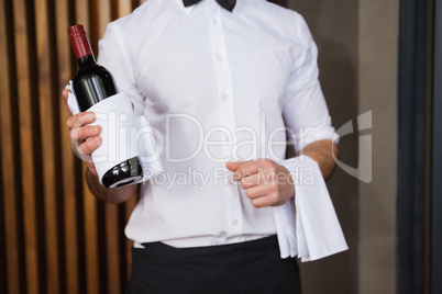 Handsome waiter holding a bottle of red wine and a towel