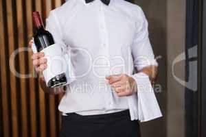 Handsome waiter holding a bottle of red wine and a towel