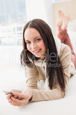 Pretty brunette sending a text on bed Pretty brunette sending a text on bed