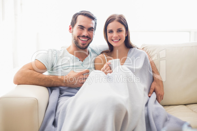 Cute couple relaxing on couch under blanket