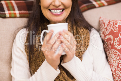 Mid section of a brunette enjoying a hot drink at christmas