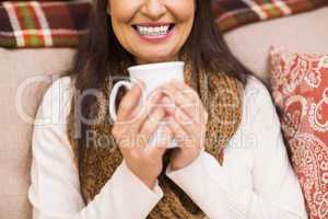 Mid section of a brunette enjoying a hot drink at christmas