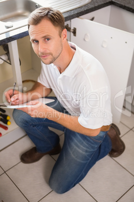 Plumber crouching and taking notes