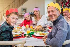 Smiling extended family in party hat at dinner table