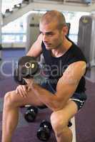 Young man exercising with dumbbell in gym