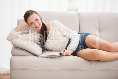 Pretty brunette reading magazine on the couch