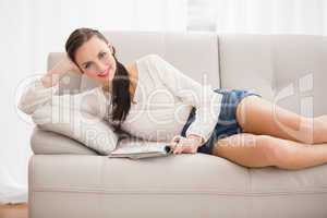 Pretty brunette reading magazine on the couch