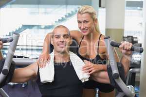 Trainer assisting man on fitness machine at gym