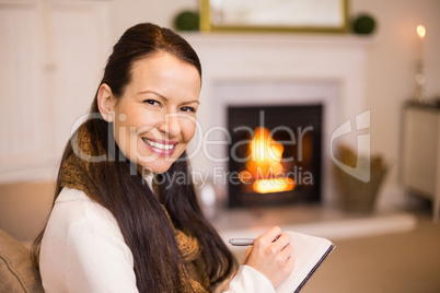 Brunette sitting on the couch writing her christmas list