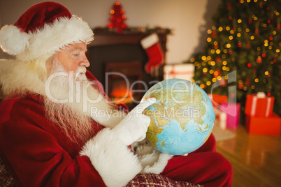 Santa claus pointing his finger on the globe