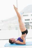 Fit brunette doing pilates on exercise mat