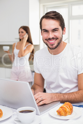 Young man using laptop at breakfast