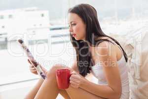 Pretty brunette sitting on floor reading magazine