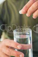 Close up of a man holding glass of water and pill