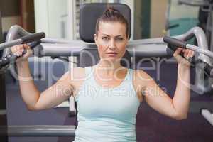 Fit brunette using weights machine for arms