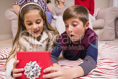 Surprised brother and sister lying opening gift