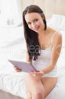 Pretty brunette using tablet pc on bed