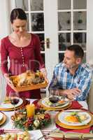 Woman serving roast turkey to her husband