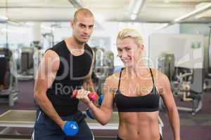 Couple exercising with dumbbells in gym