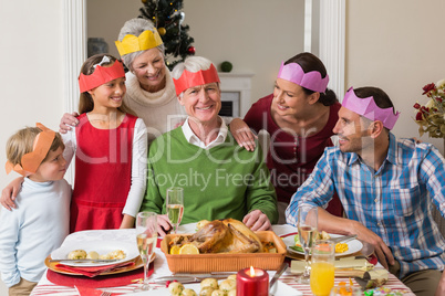 Happy extended family in party hat at dinner table