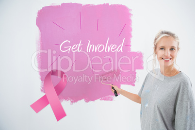 Composite image of happy young woman painting her wall pink